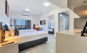 a modern hotel room with two beds , a bathroom , and a kitchenette , all situated in a well - lit area at Argus Hotel Darwin
