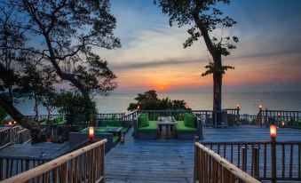 a wooden deck overlooking the ocean at sunset , with several chairs and couches placed around it at Soneva Kiri