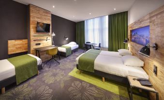 a modern hotel room with a large bed , two nightstands , and a flat - screen tv , all decorated in green and white at Nova Hotel