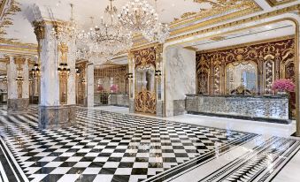 The lobby features a large, ornate room with chandeliers and tiled floors at Hotel Alexandra