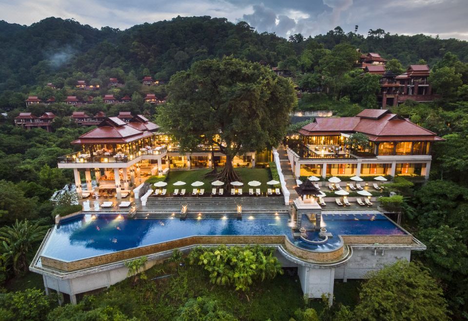a large resort with multiple buildings , a pool , and a large tree , surrounded by lush greenery at Pimalai Resort & Spa