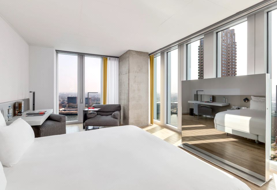 a modern hotel room with a large bed , a couch , and a window overlooking the city at Nhow Rotterdam