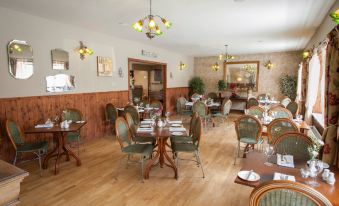 a large dining room with wooden floors and chairs arranged for a group of people at The Commercial Hotel