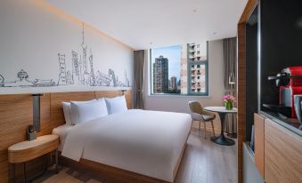A hotel room with large windows, a white bed, and a desk in the center at UrCove by HYATT Shanghai Jing'an