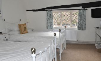 a room with two white beds , one on the left and one on the right side of the room at The Brocket Arms