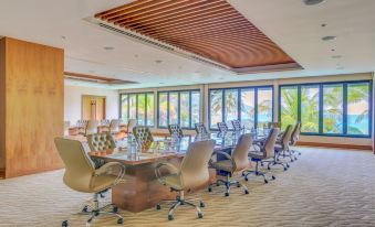 a large conference room with multiple chairs arranged around a long table , overlooking the ocean at The Taaras Beach & Spa Resort