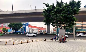 A man is sitting on the sidewalk next to an empty street with parked cars in front at Tongtong Hotel
