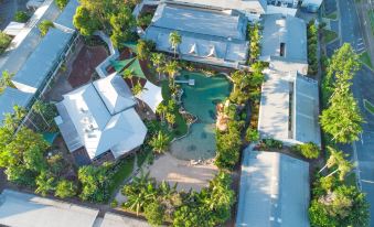 aerial view of a residential area with multiple houses , a pool , and palm trees , surrounded by greenery at Cairns Colonial Club Resort