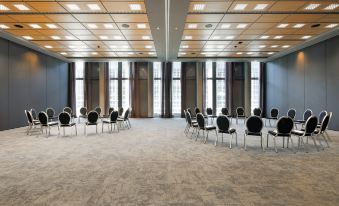 a large conference room with rows of chairs arranged in a semicircle , ready for a meeting at HYPERION Hotel Leipzig