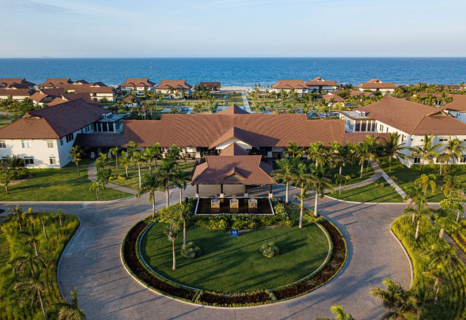 a resort with multiple buildings , surrounded by palm trees and overlooking the ocean , is seen from an aerial view at Tui Blue Nam Hoi An