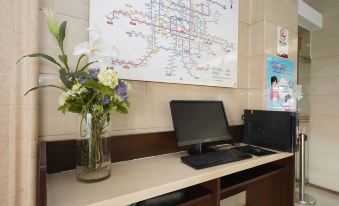 In front of the wall, there is an office with a desk adorned with flowers and books at Jingcheng Business Hotel (Beijing Shilihe Metro Station)