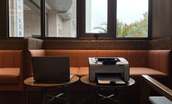 A room with windows, chairs, and tables that have computers on them in front is available at UrCove by HYATT Hangzhou Westlake