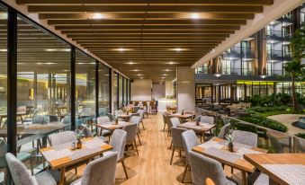 a modern restaurant with wooden floors and tables , surrounded by glass walls and large windows at Hotel Amber Pattaya