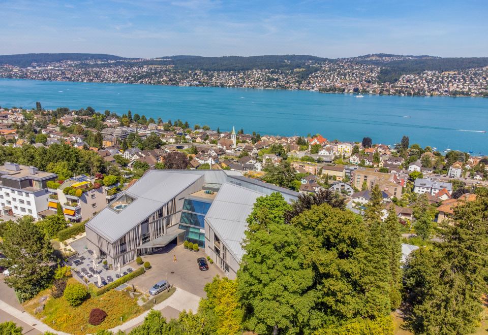 aerial view of a city with a lake in the background , surrounded by green hills and a large building at Belvoir Swiss Quality Hotel