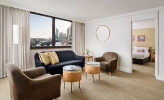 a modern living room with a black couch , two brown chairs , and a large window overlooking the city at Pan Pacific Perth