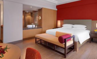 a modern hotel room with a bed , couch , and sink , along with red walls and wooden flooring at Hyatt Regency Kuantan Resort