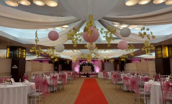 a large , elegant banquet hall with a red carpet , white drapes , and pink and white decorations at Mount Sea Resort Hotel and Restaurant Cavite