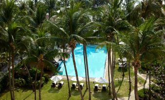 a large swimming pool is surrounded by palm trees and lounge chairs , with a view of the surrounding area at Dusit Thani Hua Hin