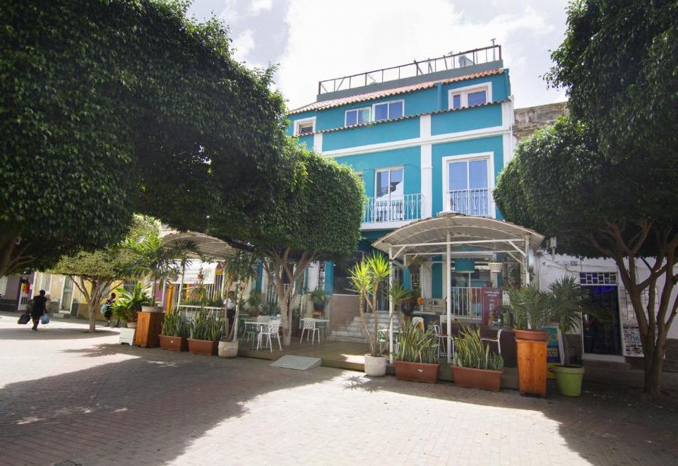 a blue building with white shutters is surrounded by potted plants and chairs in a courtyard at Hotel Santa Maria