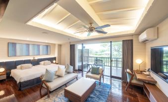 a spacious bedroom with a king - sized bed , a dresser , and a large window overlooking a balcony at Okuma Private Beach & Resort