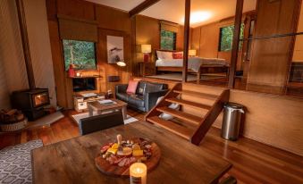 a cozy living room with wooden floors , a dining area , and a bedroom with a bed and a couch at Whispering Valley Cottage Retreat