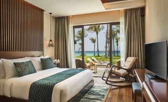 a bedroom with a bed , chairs , and a view of the ocean through large windows at Movenpick Resort Cam Ranh