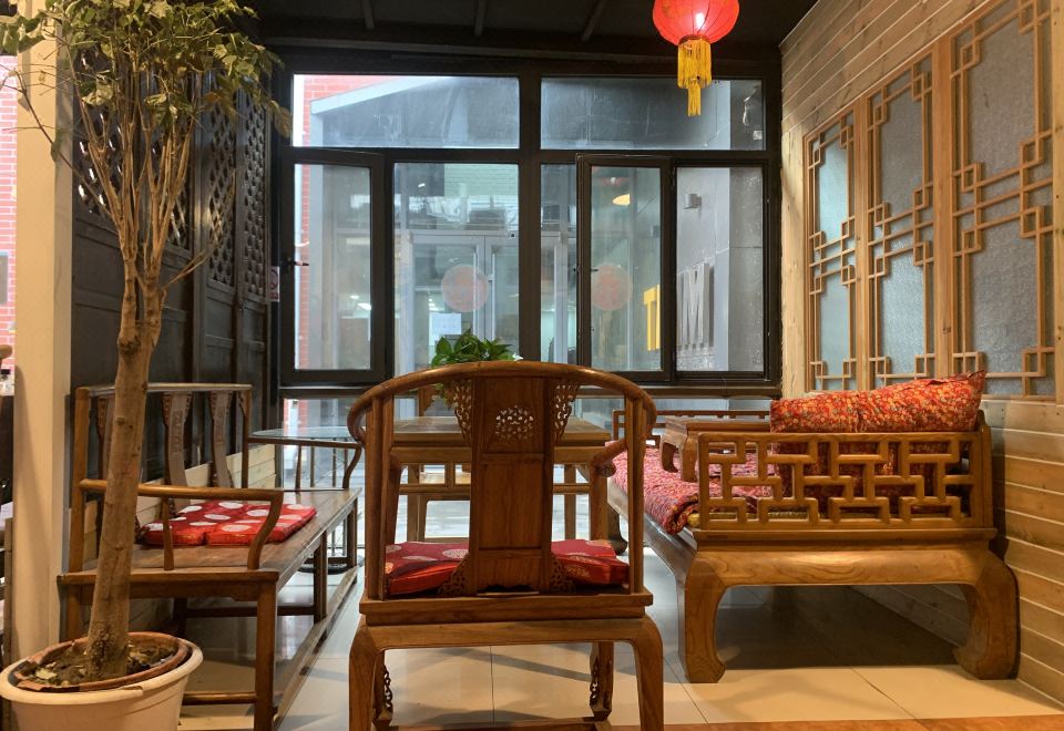 The room features wooden furniture and tables, with an enclosed window offering a picturesque view of the city at Paoju Factory Youth Hostel (Beijing Summer Palace Subway Station Branch)