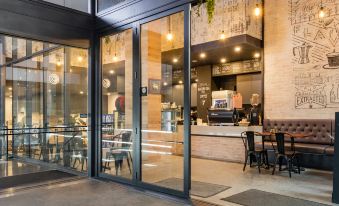 a modern cafe with large glass windows and wooden chairs , creating an open and inviting atmosphere at Meriton Suites North Sydney