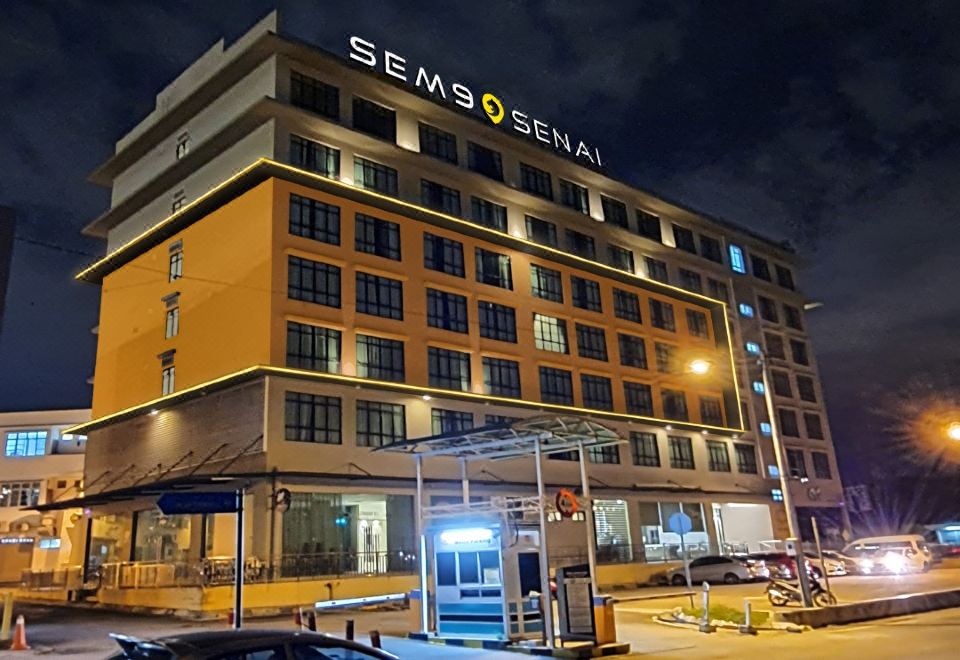 "a tall building with the word "" sensi senai "" lit up in blue and white letters on its facade" at Sem9 Senai "Formerly Known As Perth Hotel"