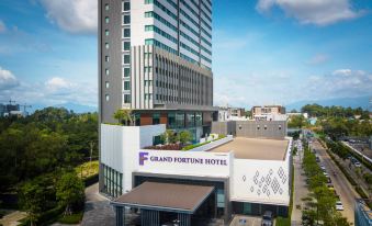 the grand fortune hotel , a modern building with a white exterior and large windows , surrounded by trees and mountains at Grand Fortune Hotel Nakhon Si Thammarat