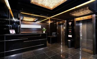 The lobby features black walls and wood paneling, with a centrally located illuminated bar at J Link Hotel