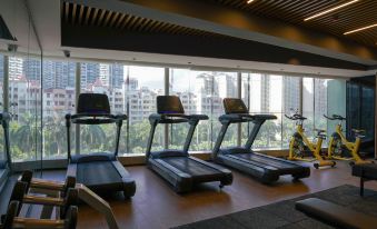 A room with large windows and various types of treadmills in front at Paco  Hotel (Jiangmen Xinhui Times)