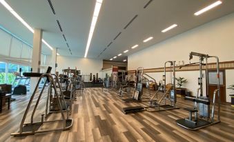 There is a spacious ground floor room with multiple exercise equipment and wood paneling at Ambassador Hotel Bangkok