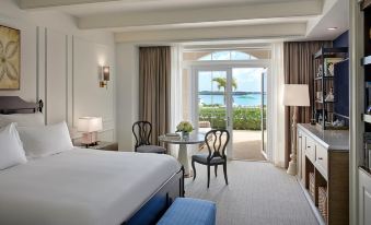 a luxurious hotel room with a large bed , two chairs , and a view of the ocean through a window at Rosewood Bermuda