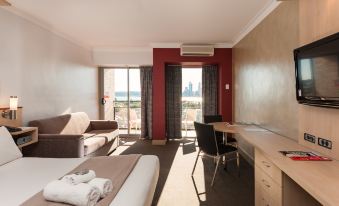 a hotel room with a bed , desk , and couch , as well as a view of the ocean at Metro Hotel Perth