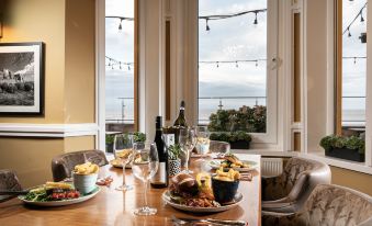 a dining table is set with plates of food , wine glasses , and a bottle of wine at Cbh the Beaches Hotel