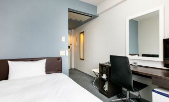a modern hotel room with a white bed , desk , and chair , as well as a mirror on the wall at Hotel Wing International Miyakonojo