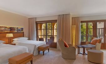 a hotel room with two beds , a couch , and a chair near a window with curtains at Sheraton Mallorca Arabella Golf Hotel