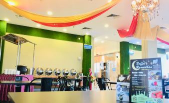 a modern restaurant with green walls , white columns , and gold chandeliers , featuring a long bar counter with multiple lights at Sem9 Senai "Formerly Known As Perth Hotel"