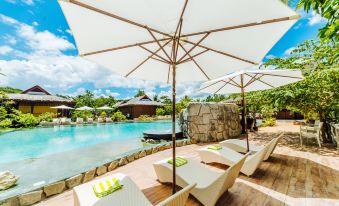 a beautiful outdoor setting with umbrellas , chairs , and tables on a wooden deck overlooking a pool at Loboc River Resort