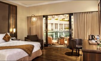 a modern hotel room with a large bed , two chairs , and a balcony view of a courtyard at The Singhasari Resort Batu
