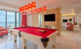 a billiards table in a modern living room , with red billiard balls on the table and chandeliers hanging from the ceiling at Grand Hyatt Baha Mar