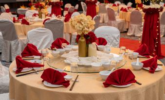a well - decorated banquet hall with multiple tables set up for a formal event , featuring white tablecloths , red napkins , and at Travelodge Ipoh