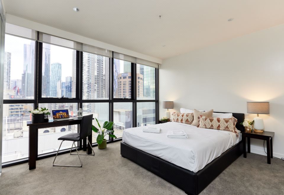 a modern bedroom with a large window and a comfortable bed , creating a view of the city at Arrow on Swanston