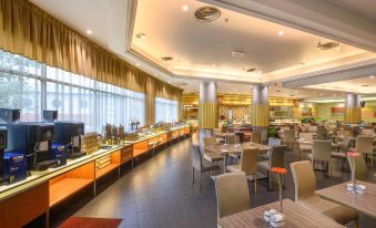a large dining area with numerous tables and chairs , as well as a buffet table filled with food at Cititel Penang