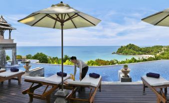 a man is standing on a deck overlooking the ocean , preparing to lounge on a lounge chair at Pimalai Resort & Spa