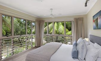 a spacious bedroom with a large bed and a view of a garden through the large window at Mantra Amphora