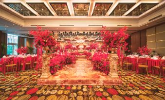 The room is spacious and adorned with red flowers on the tables, while its floor-to-ceiling windows are elegantly trimmed in gold at Kempinski Hotel Beijing Yansha Center