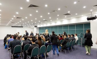 a large group of people gathered in a conference room for an event , with several chairs arranged around them at Arrow on Swanston