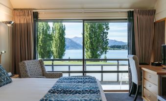 a room with a large window overlooking a lake and mountains , featuring a bed and a chair at Edgewater Hotel